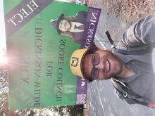 Nick wearing a Sooke Horseshoe Players hat with one of his election signs on his backpack.